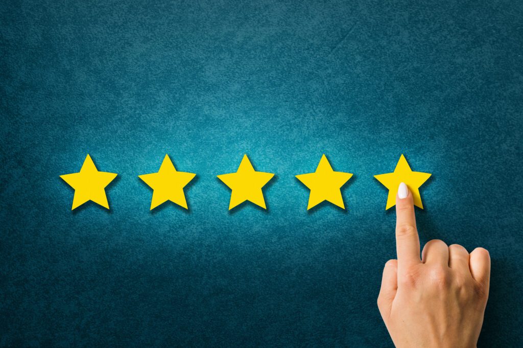 Finger of a hand touching 5th star on yellow stars review