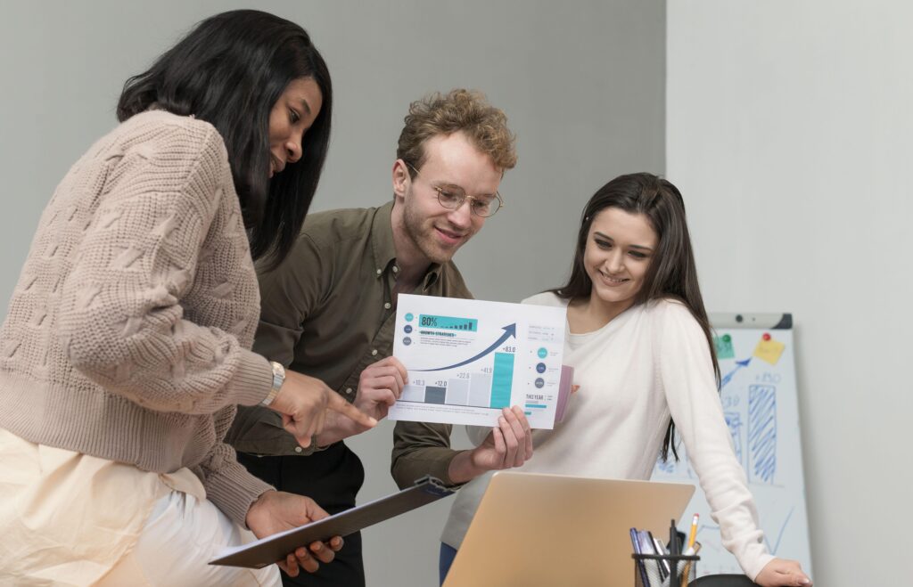 Group of employees dicussing growth of business via charts and laptop