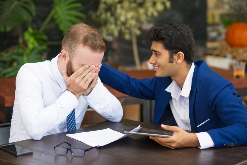 A blue shirt man supporting the white shirt man who is crying showcasing how to deal with unhappy customers