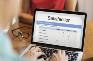 Online satisfaction rating on laptop with glasses on table